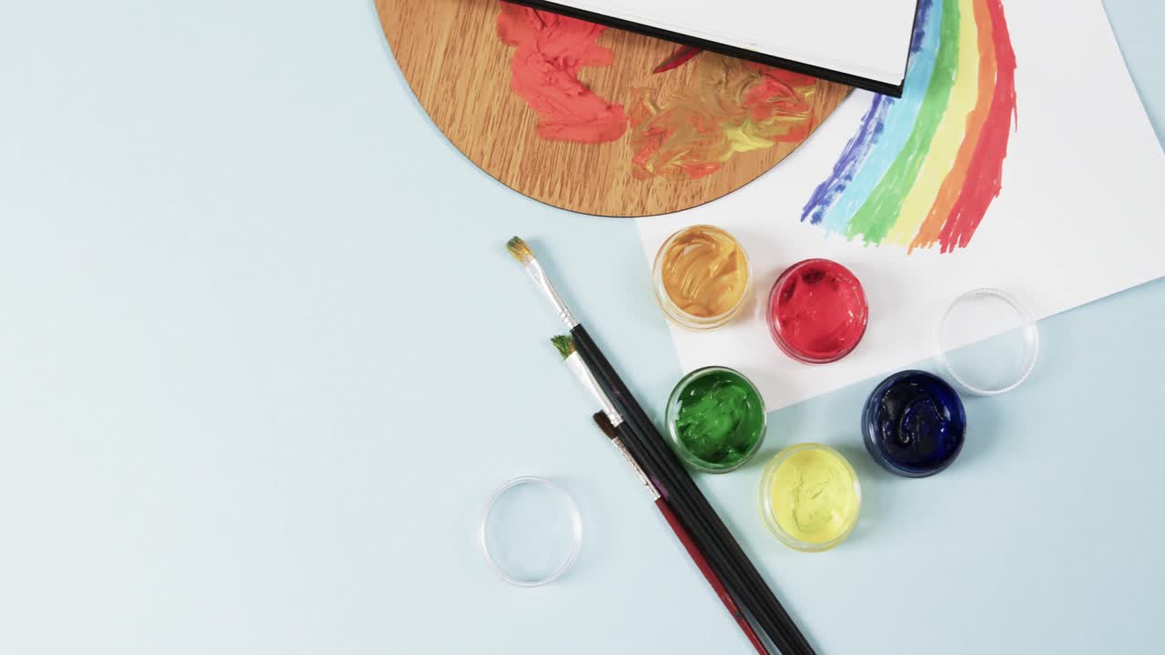 녹화 공간과 함께 파란색 배경에 노트북, 질 및 페인트의 오버헤드 뷰, 느린 동작