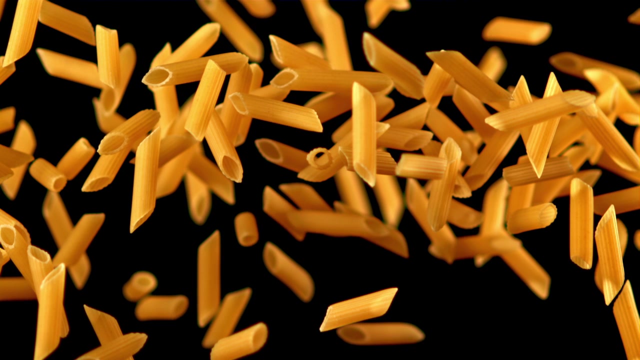 Pasta penne cruda che cade e fluttua al rallentatore