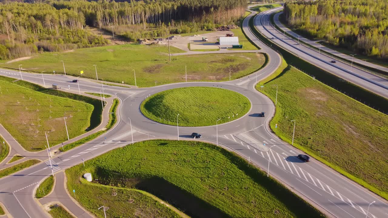 Aerial orbit of modern suburban highway interchange with looping roads in spring, roundabout traffic circle