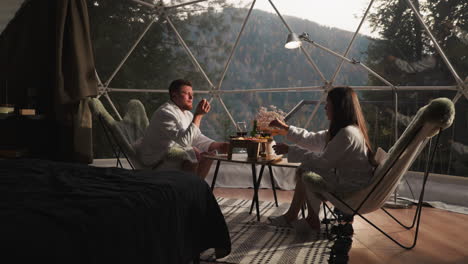 couple enjoying a romantic breakfast/dinner in a glamping dome with mountain view