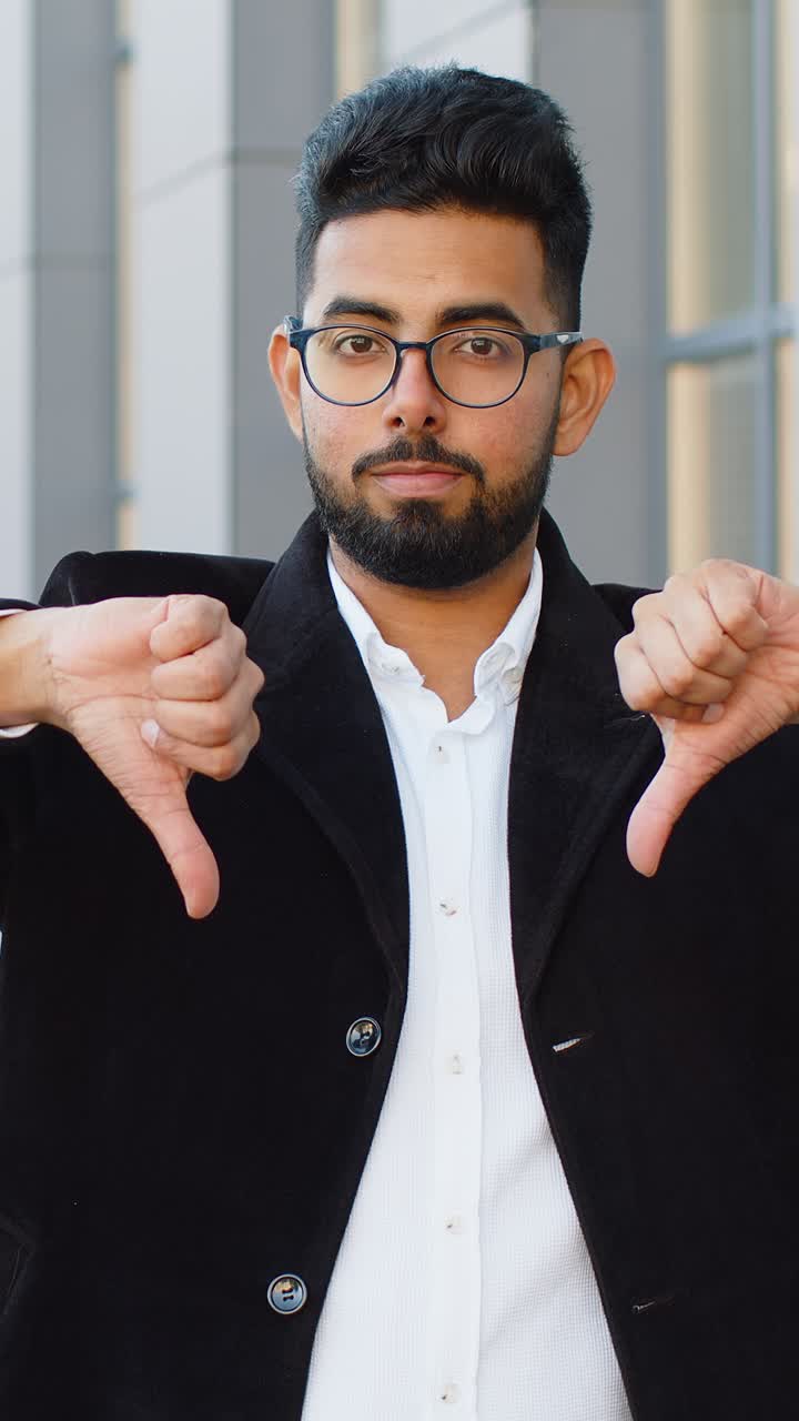 Upset business man showing thumbs down sign disapproval dissatisfied bad work mistake in city