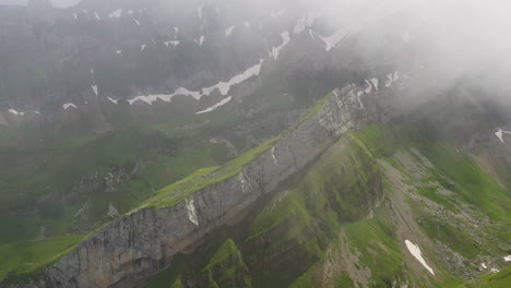 Disparo-De-Dron-En-ángulo-Descendente-De-Altenalp-Turm,-Comenzando-En-Las-Nubes-Y-Luego-Revelando-La-Ladera-De-La-Montaña