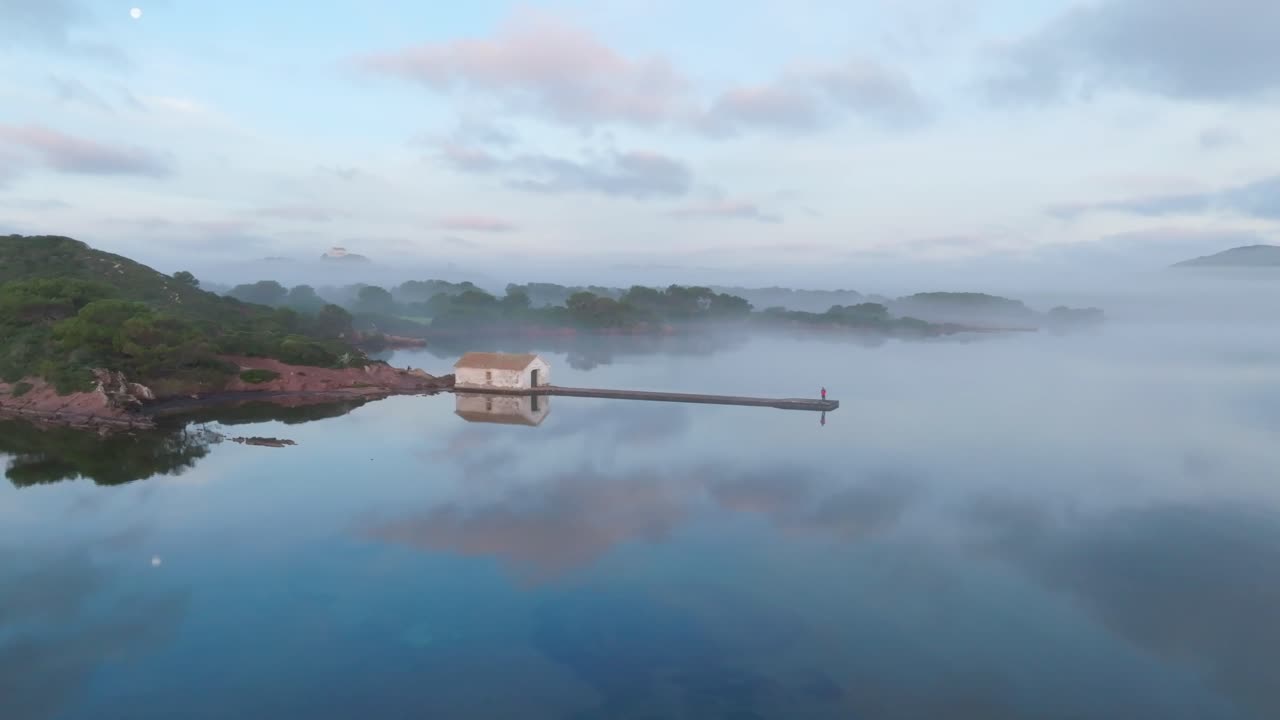 nubes reflejadas en la bahía agua tranquila islote acantilado verde línea costera dron estableciendo tiro aéreo