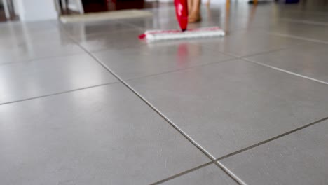a mop glides over a tiled floor, spraying water in slow motion, highlighting cleaning action and technique