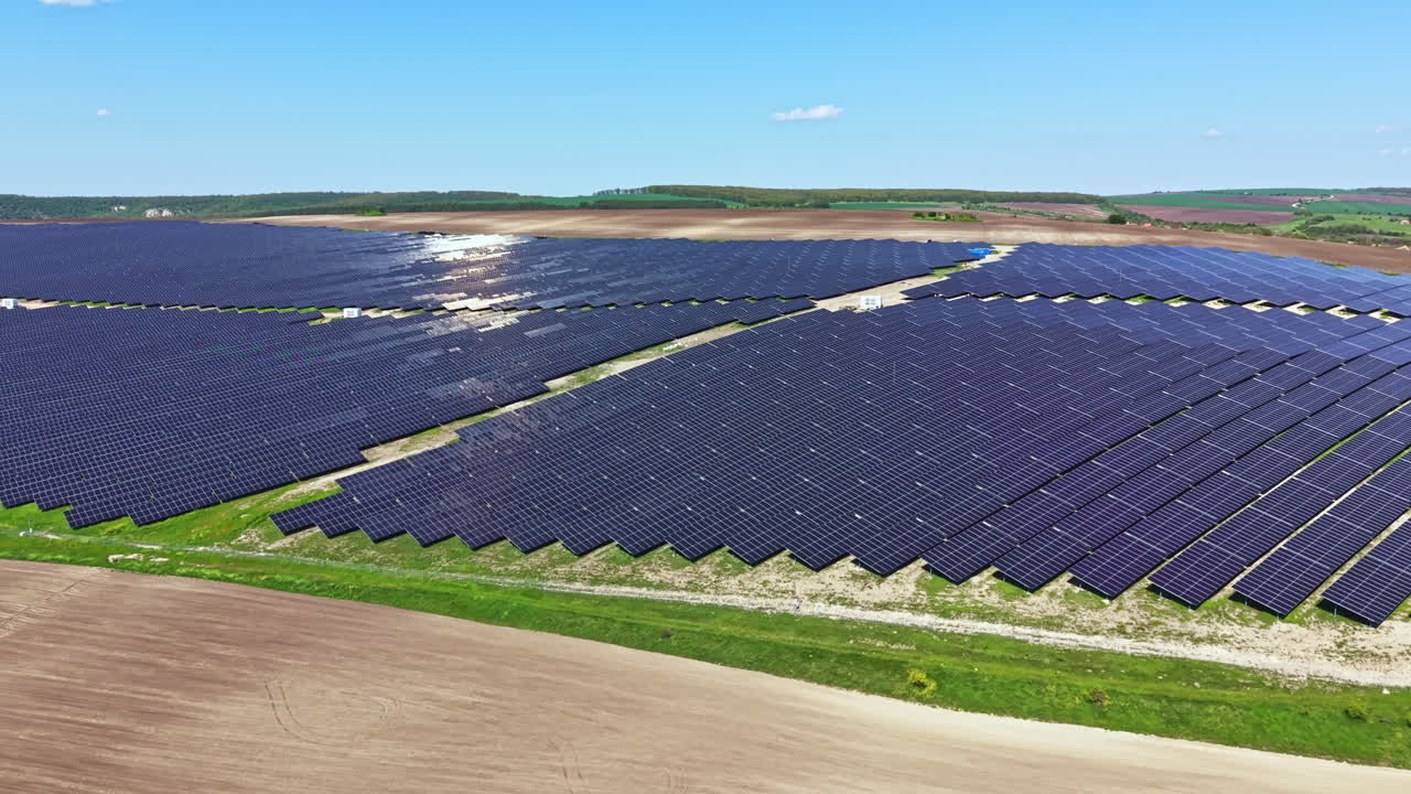 Stor solcellepark med mange solpaneler på landet på en lys solskinsdag.