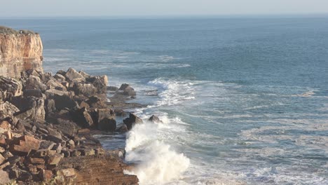 mountain being washed by the sea in cascais