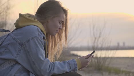 sunset beach and girl using smartphone for chatting