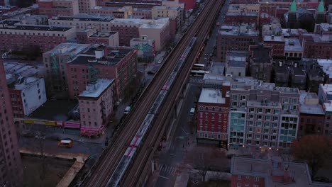 aerial trucking shot toward a commuter train moving through the buildings of harlem new york city just after daybreak