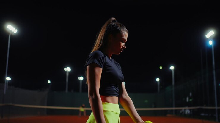 Frau spielt Tennis bei Nacht