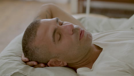 Peaceful-Caucasian-man-sleeping-in-morning-with-head-behind-head