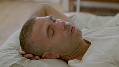 peaceful caucasian man sleeping in morning with head behind head