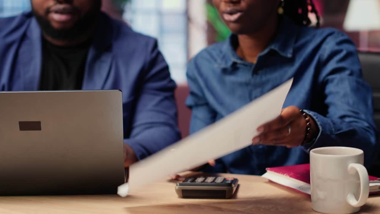 Black man and woman analyzing financial documents and tracking expenses