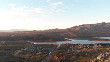 Una-Foto-De-Un-Dron-Que-Muestra-Una-Carretera-Junto-Al-Lago-Al-Atardecer