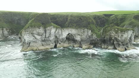 acantilados de piedra caliza blanca con arcos en la costa de antrim en portrush, irlanda del norte