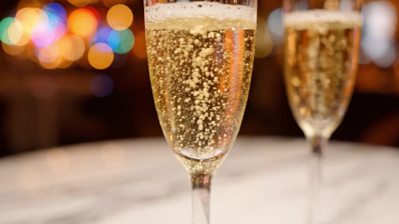Brindisi celebrativo con champagne frizzante: una vista ravvicinata di due eleganti flûte piene di bollicine, poste su uno sfondo delicatamente illuminato, perfette per occasioni speciali.