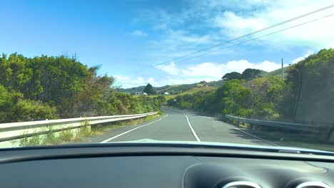 a car journey on a sunny day along the winding great ocean road, surrounded by lush greenery and clear blue skies