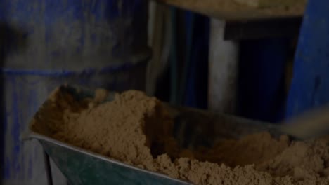 animation of stock market data processing over mid section of man putting saw dust in storage tank