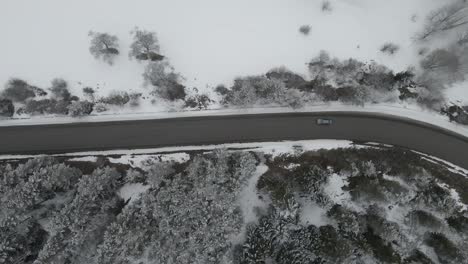 A-picturesque-winding-road-cutting-through-a-dense-forest,-blanketed-in-fresh-snow,-capturing-the-serene-beauty-of-a-winter-wonderland