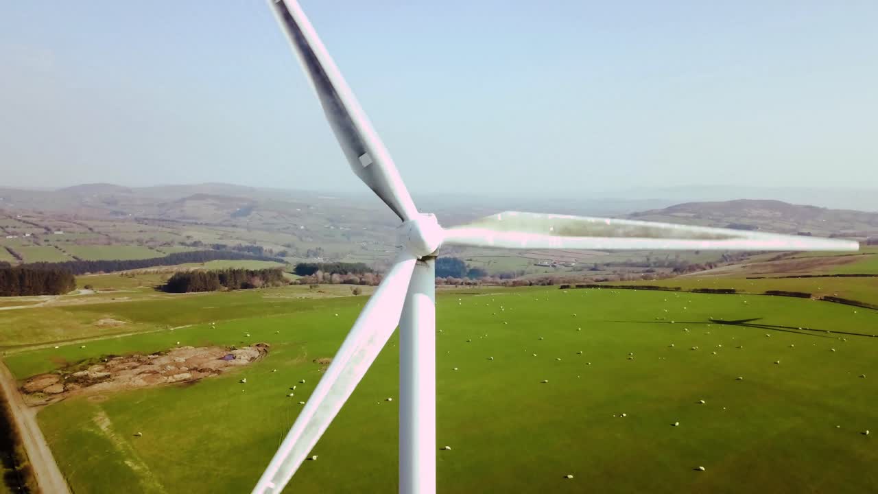 Slow pullback shot of active wind turbine generating power. Pull back slow from centre of turbine to reveal full turbine span