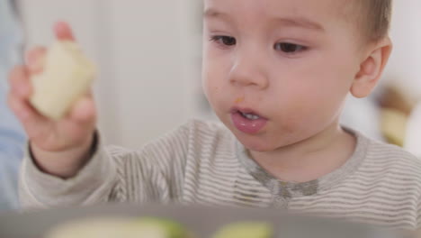 close up of an adorable baby boy eating banana at home