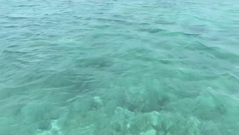 pan up off of water past sailing boat to island, san blas islands, panama. drone pan up off of water up and away hd