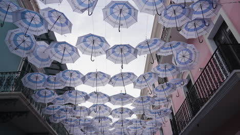 slow motion tilting shot of symmetrical umbrellas hanging in the streets of san juan