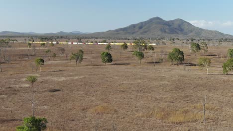 Freight-train-crossing-desolate-land-at-St-Lawrence,-Clairview-in-Australia