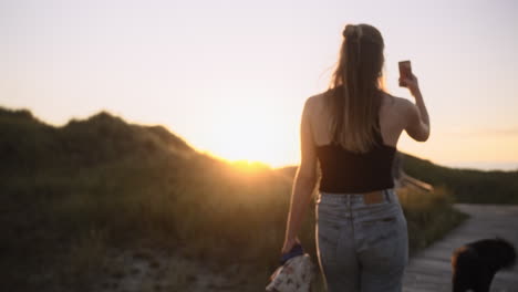 woman films herself at the beach while sunset