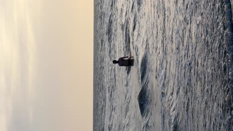 vertical video of young man taking a dip in the sea during his vacations