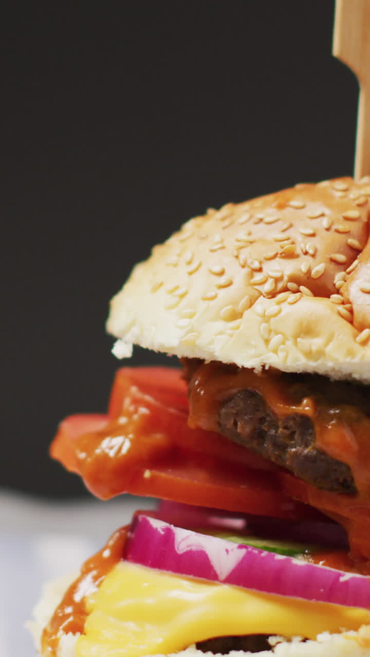video de primer plano de una hamburguesa de queso en un pan de hamburguesa con horquilla de madera, sobre un fondo gris con espacio para copiar