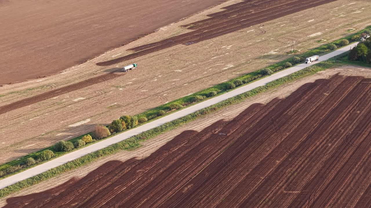 Top view of agricultural machinery spreading fertilizer over a cultivated field