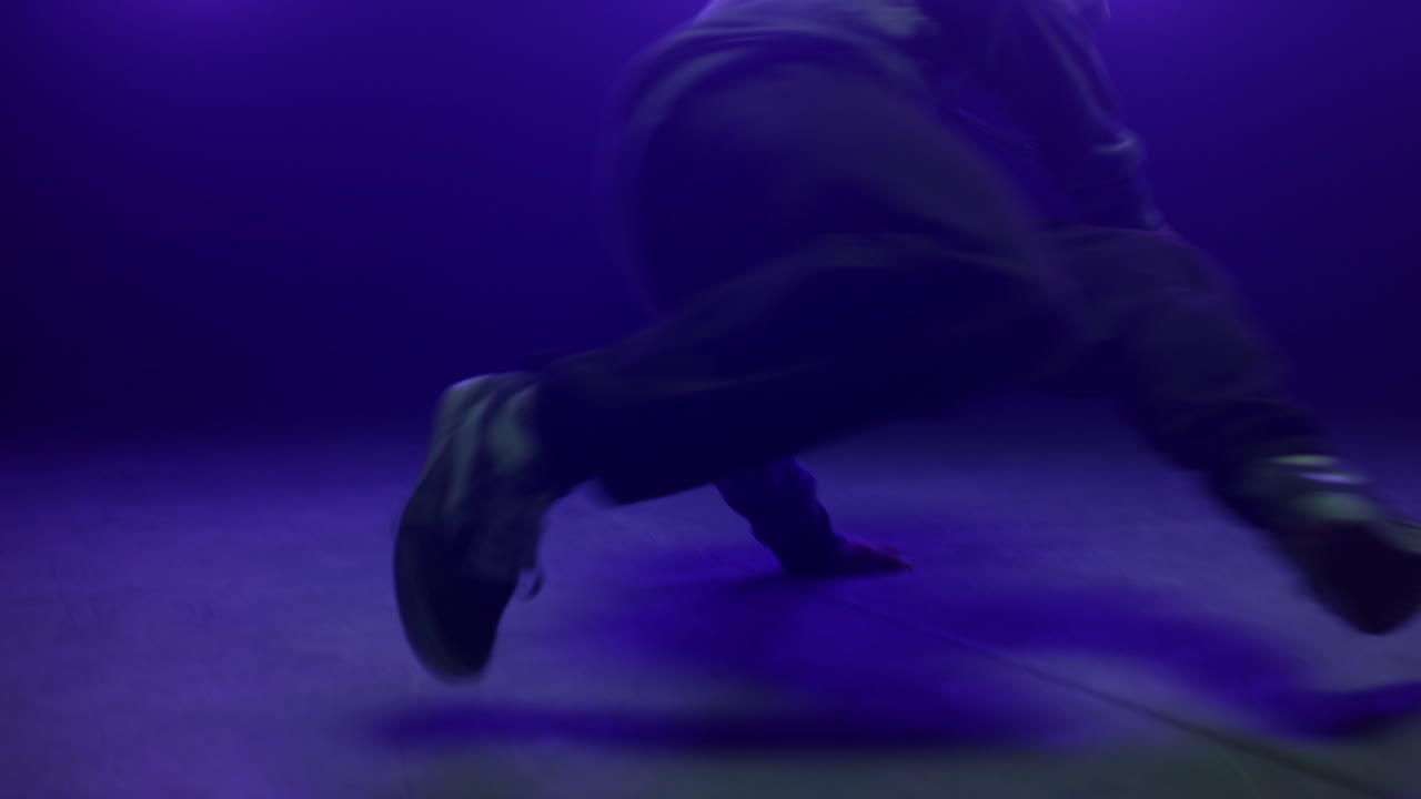 Performer talentuoso che fa breakdance in discoteca, retroilluminato da luce ultravioletta. Silhouette di un ballerino.
