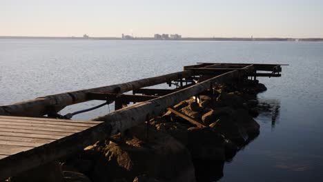 a dynamic shot of a broken jetty moving from the footpath towards the open water to the horizon