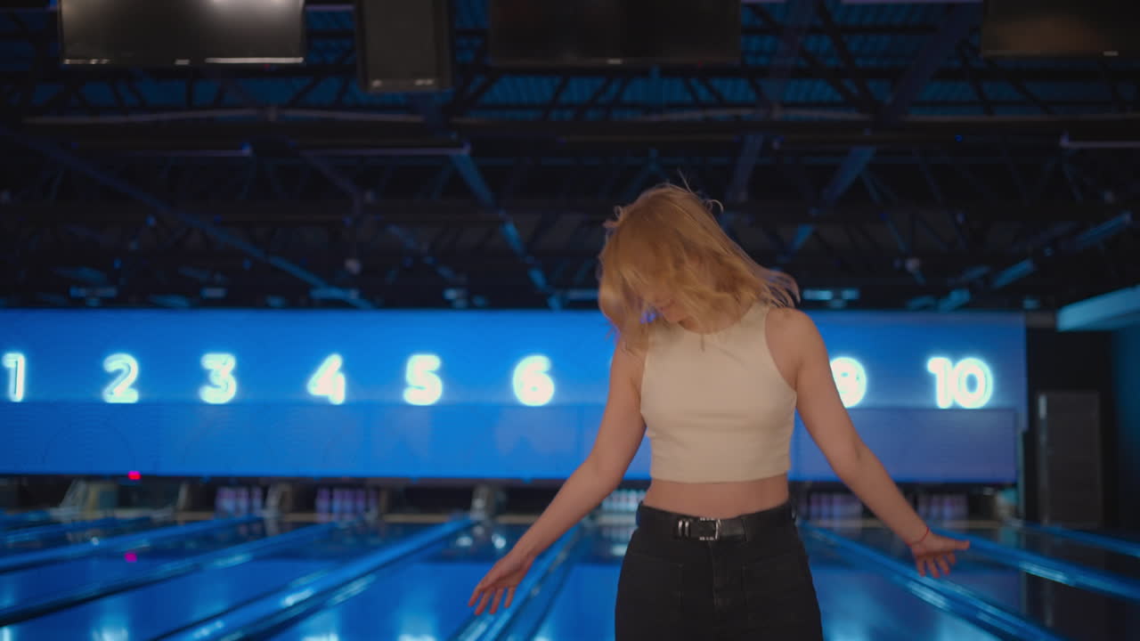 retrato mulher jovem saltar feliz olhando para a câmera comemorar a vitória em câmera lenta. jogar na pista de boliche para fazer uma filmagem. dança vitória e saltar com felicidade.