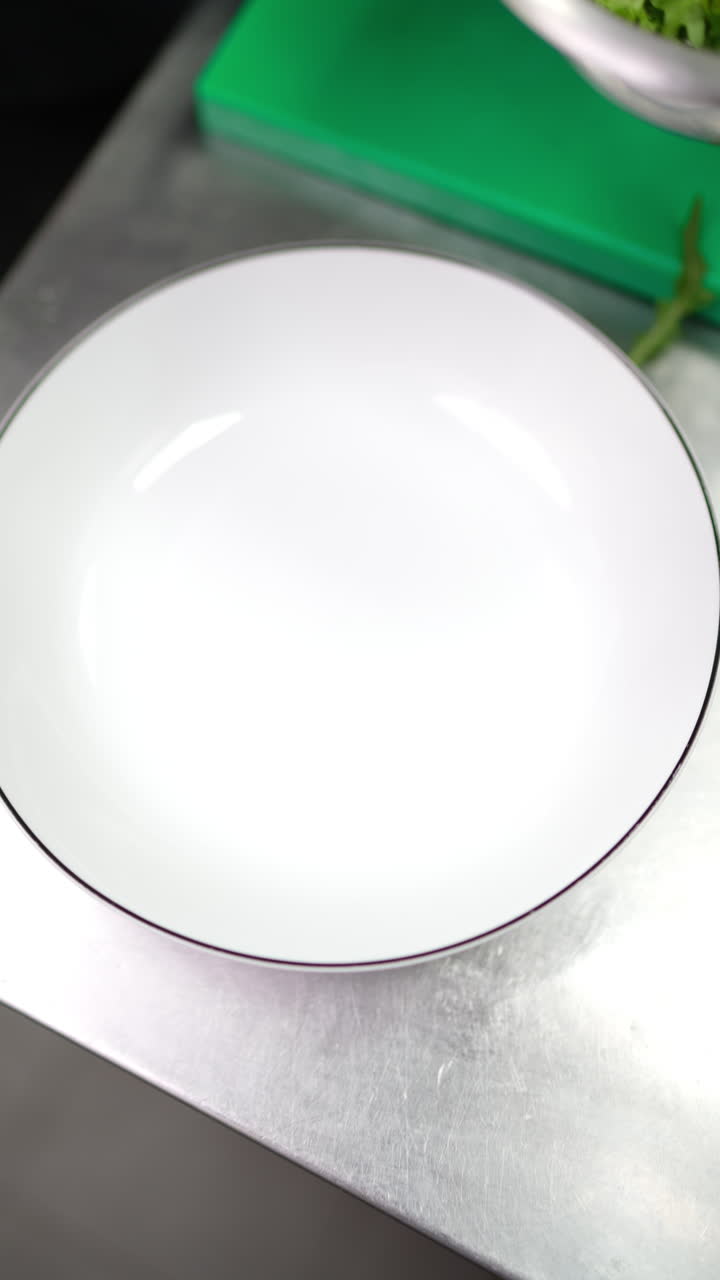 Vertical footage Gloved hands positioning delicate arugula leaves precisely on pristine porcelain plate, crafting elegant culinary presentation