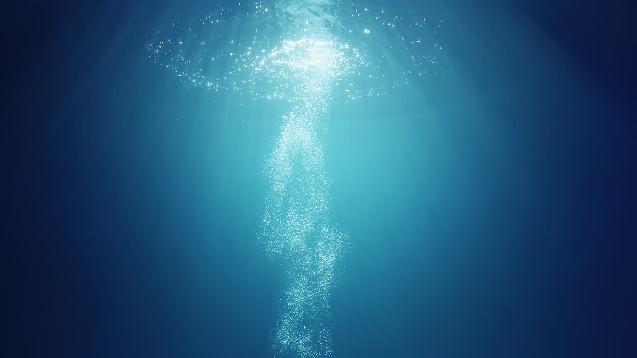 위에서부터 빛나는 수중 햇빛 광선이 깊고 맑고 푸른 물을 통과하여 수면 위로 올라오는 기포가 있는 아름다운 물 조명 반사 커튼을 만듭니다.