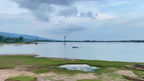 pan left view from riverside with row of traditional wooden boats beside river in sylhet on overcast day