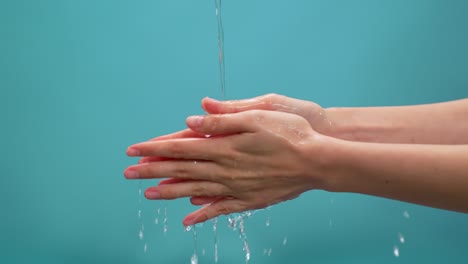깨한 물의 스플래시가 파란색 배경의 손으로 흘러 들어가며, 물을 절약하는 개념은 오랫동안 지속될 수 있도록합니다.