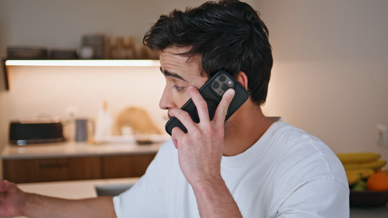 아파트 주방에서 스무디를 마시면서 스마트폰으로 통화하는 남자의 클로즈업