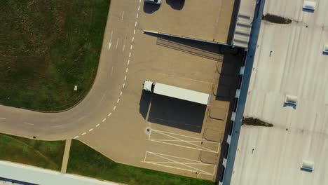 Aerial-view-of-a-semi-trailers-trucks-standing-at-the-warehouse-ramps-for-load-unload-goods-in-the-logistics-park