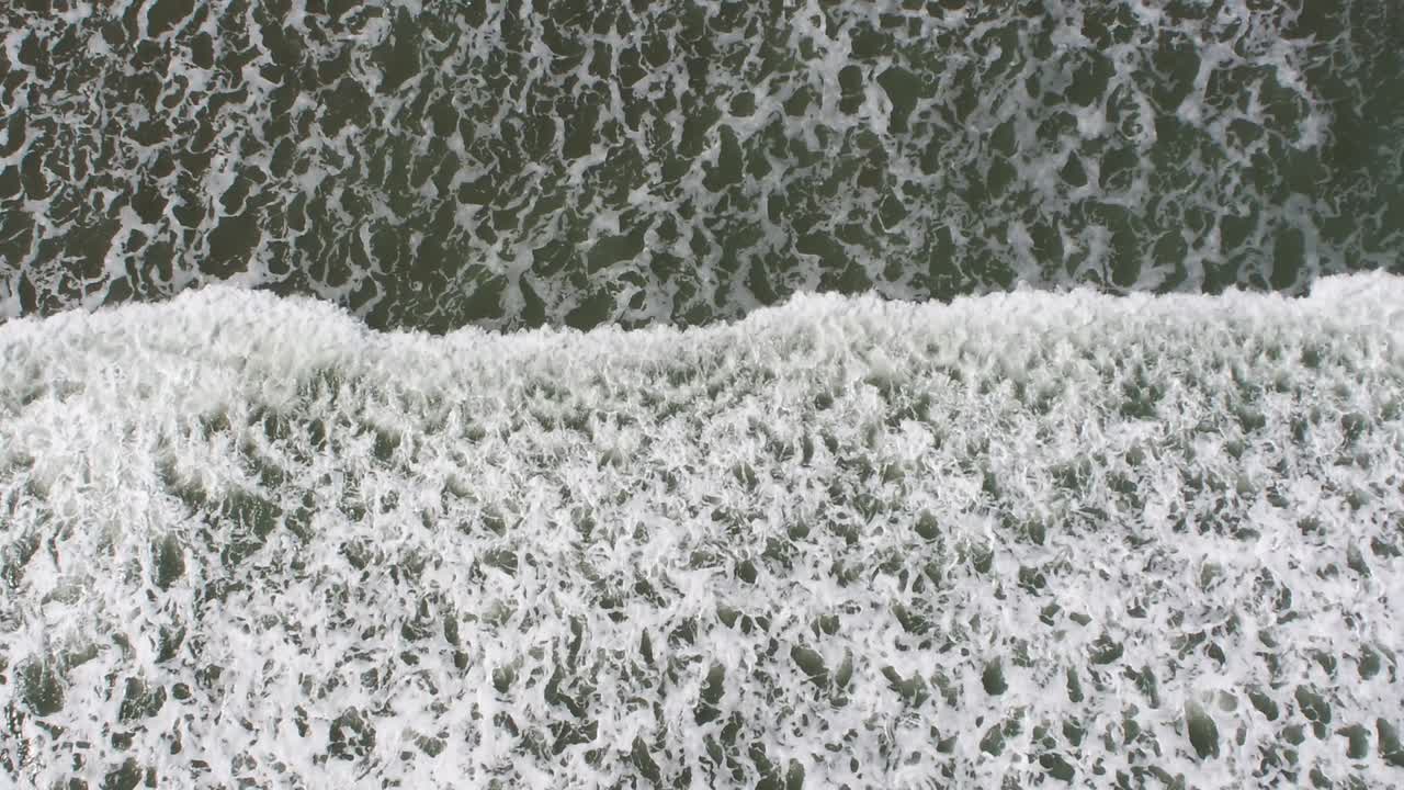 Aerial bomb shot of breaking waves at low tide in late summer