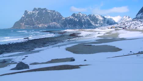 las olas ruedan hacia una hermosa playa cubierta de nieve en medio de fiordos al norte del círculo polar ártico en las islas lofoten noruega