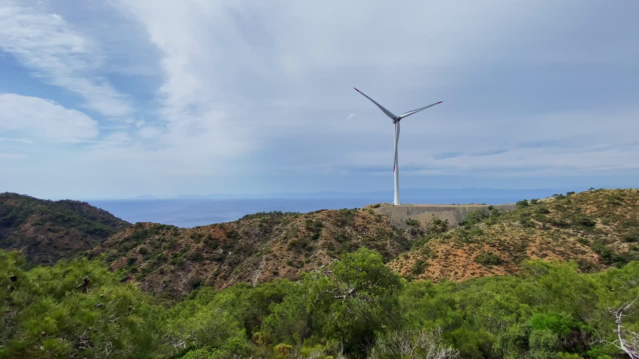 Sustainable Resources – Single wind turbine tower among wild pine tree valley landscape of Datça peninsula under overcast sky, Aegean Turkey