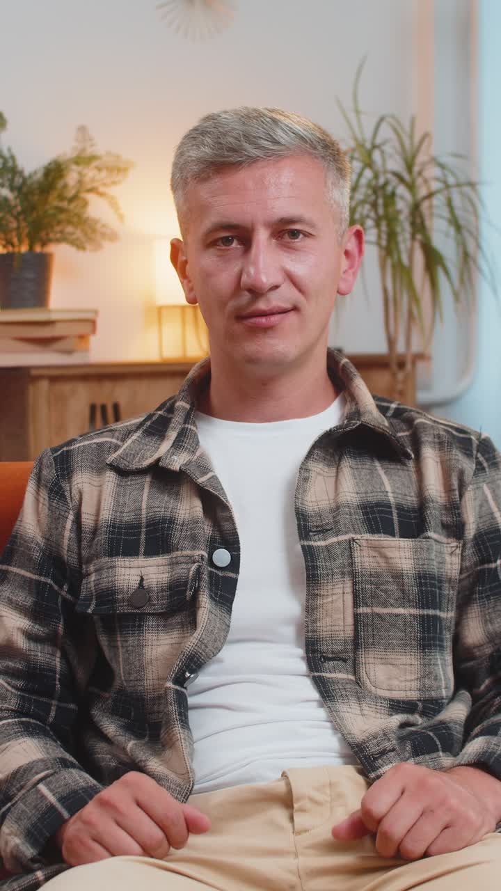 hombre sonriente en casa hace símbolo de amor mostrando el corazón señal a la cámara expresar sentimientos románticos