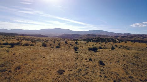 Aerial-flight-over-open-land-toward-a-mountain-range,-Sedona,-Arizona