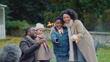 Family-having-fun-with-sparklers-in-autumn-garden-at-home---shot-in-slow-motion