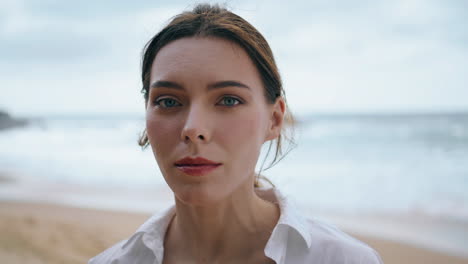 beautiful gentle woman face looking camera intently at sea vertically close up.