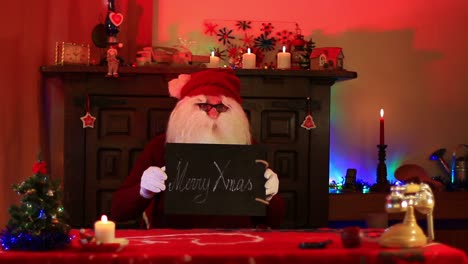 santa claus mostrando nota de feliz navidad en pizarra negra