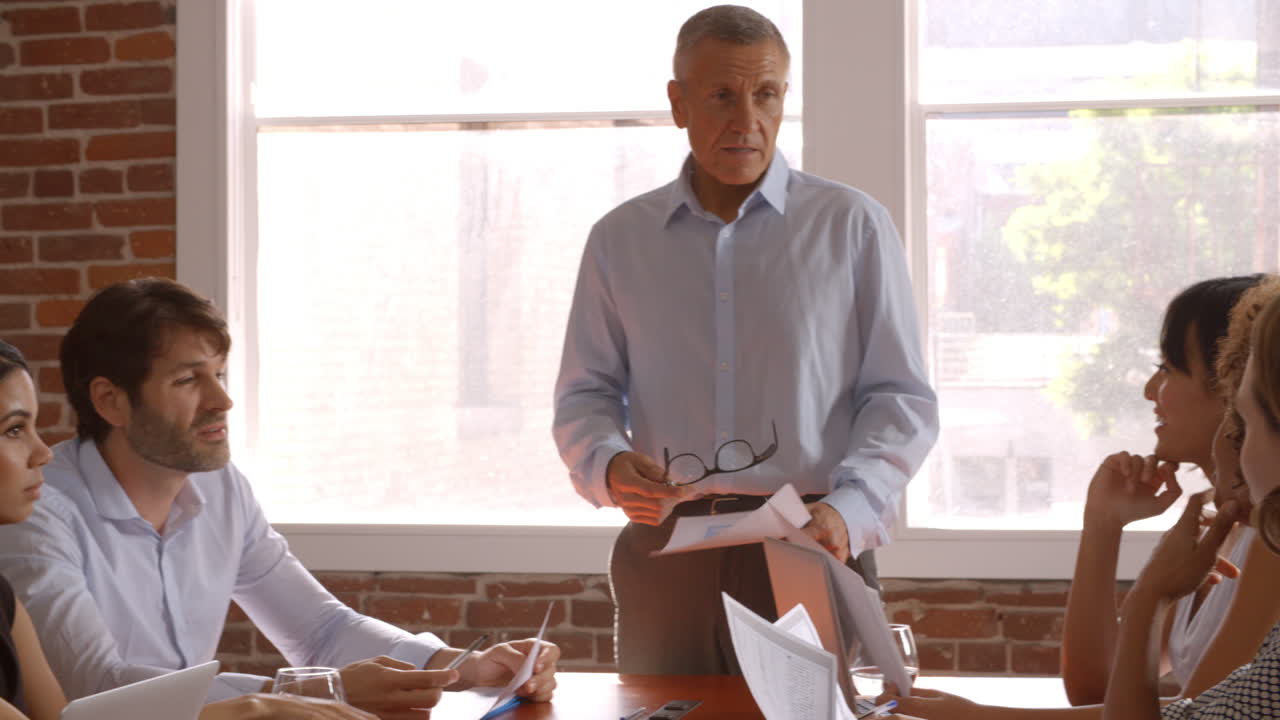 성숙 한 사업가 가 이사회 회의 에서 연설 하기 위해 서 있는 것