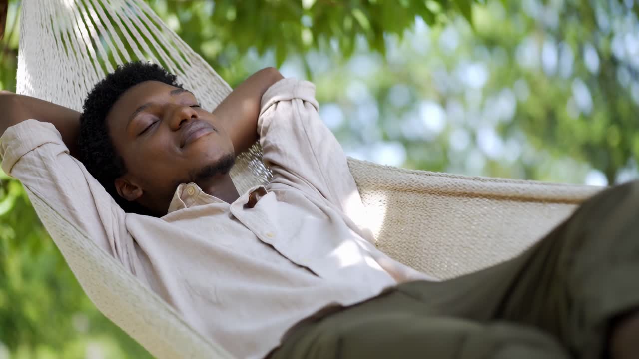 Homem relaxado em uma rede, foto em ângulo baixo, ambiente externo sereno. Perfeito para um vídeo de estilo de vida